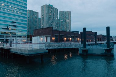 port and pier on Hudson river near modern buildings in New York City clipart