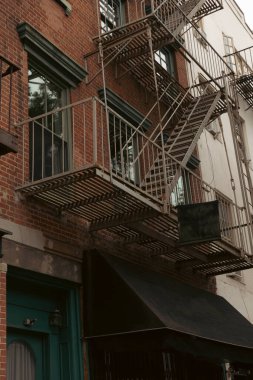 New York 'ta metal balkonları ve yangın merdivenleri olan kahverengi tuğlalı ev.