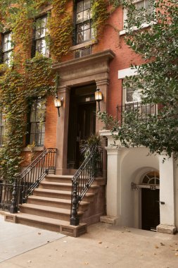 house with ivy and lanterns near entrance on urban street in Brooklyn Heights district of New York City