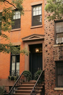 stone building with potted plants on stairs and lantern above entrance in New York City