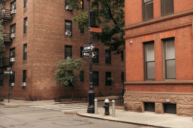 Pointers between brick buildings on street in New York City clipart