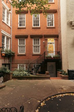 Urban street with fallen leaves on road and brick buildings in New York City