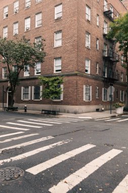 Corner of brick house and crosswalks on road on street in New York City clipart