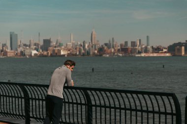 NEW YORK, USA - OCTOBER 11, 2022: Man standing on Hudson river waterfront walkway at daytime 