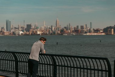 NEW YORK, USA - OCTOBER 11, 2022: Man standing on Hudson river waterfront walkway at daytime  clipart