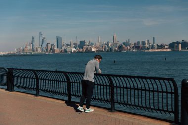 NEW YORK, ABD - 11 Ekim 2022 Hudson Nehri rıhtım yolunun çitlerinin yanında duran adam 