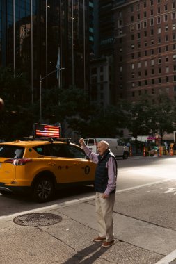 NEW YORK, USA - OCTOBER 11, 2022: Man catching taxi on urban street in Manhattan