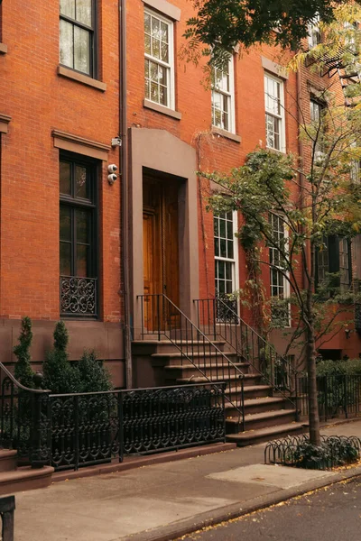 Trees and fence near brick building on street of brooklyn heights in New York City