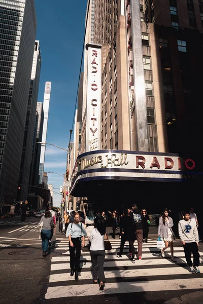 NEW YORK, USA - OCTOBER 11, 2022: Pedestrians walking on crosswalk near music radio hall on urban street 