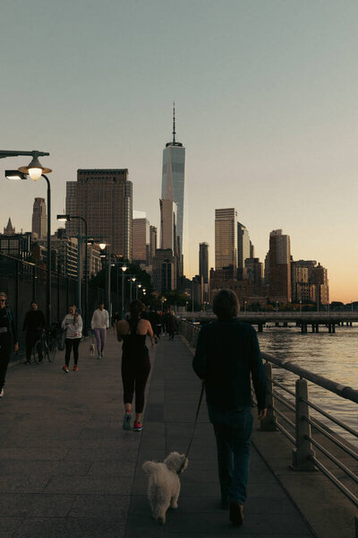 NEW YORK, USA - OCTOBER 11, 2022: People walking on street near Hudson river in evening 