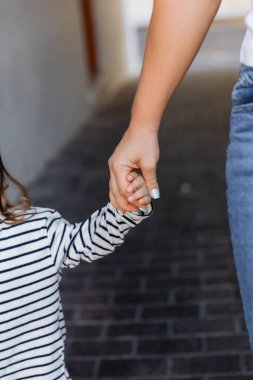 cropped view of mother and daughter holding hands outdoors  clipart