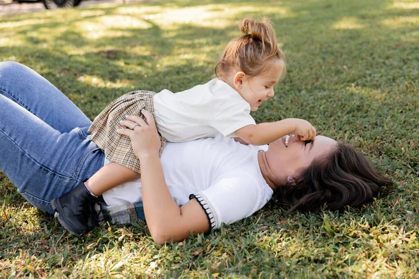 Vrolijk Moeder Liggend Groen Gazon Met Glimlachende Peuter Baby Meisje — Stockfoto
