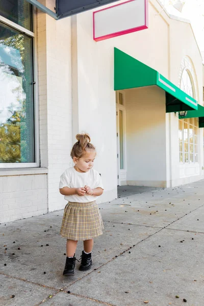 Etek ve beyaz tişörtlü bir çocuk Miami 'de meşe palamudu seyrediyor. 