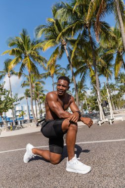 Miami 'deki palmiye ağaçlarının yanında dinlenen üstsüz Afro-Amerikan sporcusu