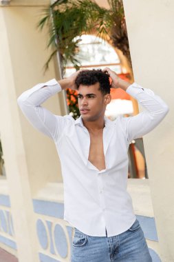 Miami, güney sahilinde, binanın yanında duran beyaz gömlekli ve kot pantolonlu rahat genç Kübalı adam.