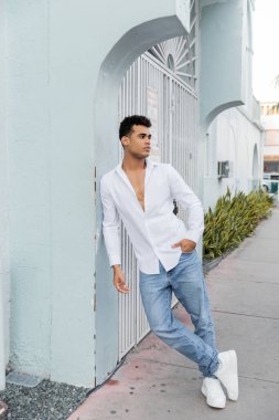Miami 'de sokakta poz veren şık gömlekli ve kot pantolonlu yakışıklı Kübalı adam.