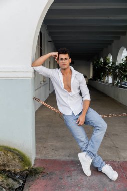 Miami 'de şehir sokağında beyaz gömlekli ve kot pantolonlu şık bir Kübalı.