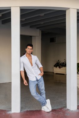 Miami 'de duran yuvarlak gözlüklü, beyaz gömlekli ve kot pantolonlu şık Kübalı adam.