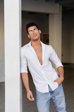 Yuvarlak gözlüklü ve cebinde beyaz gömleği olan son moda Kübalı genç adam. 
