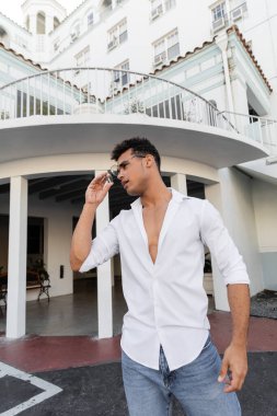 Beyaz gömlekli ve kot pantolonlu rahat Kübalı adam Miami 'de şık yuvarlak gözlükler takıyor.