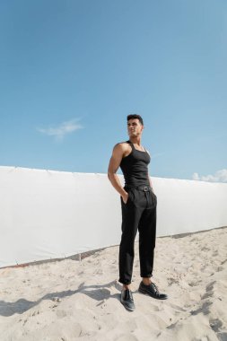 Miami, Güney Sahili 'nde siyah kolsuz tişört ve pantolon giyen atletik genç Kübalı adam