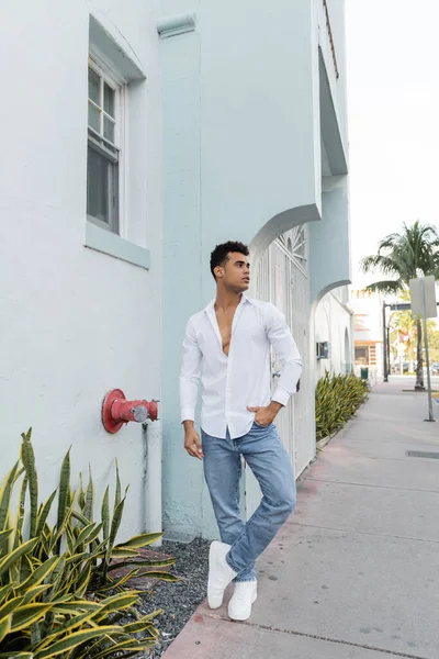 stock image Full length of curly cuban man in stylish shirt and blue jeans posing on street in Miami
