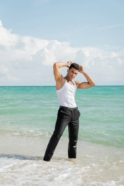 muscular young Cuban man standing in ocean water in Miami South Beach, Florida