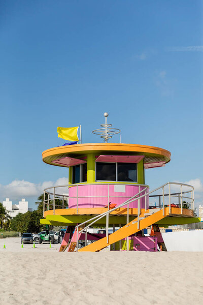 Colorful beach lifeguard tower with flags on top on sand with blue sky at background in Miami 