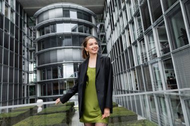 Berlin, Almanya 'da ceketli ve yeşil ipek elbiseli güzel ve zarif bir kadın gülümsüyor. 