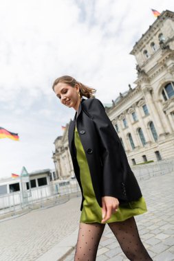 Berlin, Almanya 'da Reichstag Binası yakınlarında yeşil ipek elbiseli neşeli bir kadın yürüyor. 