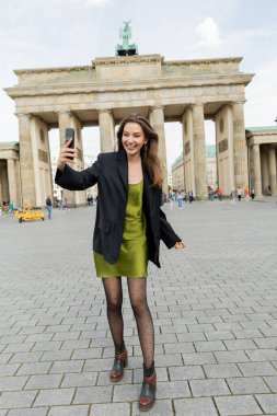 BERLİN, ALMANY - 13 MAYIS 2022: Berlin 'deki Brandenburg Kapısı yakınlarında selfie çeken mutlu kadın