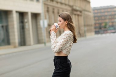 trendy young and pretty woman in lace top and high waist pants drinking coffee to go  clipart