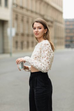 Açık renk pantolonlu ve dantelli genç bir kadının portresi. Berlin 'e gitmek için elinde kahve vardı.