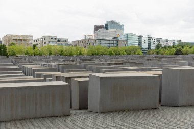 View of Memorial to the Murdered Jews of Europe with buildings at background outdoors in Berlin clipart
