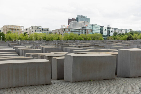 Вид на Мемориал убитым евреям Европы со зданиями на заднем плане в Берлине