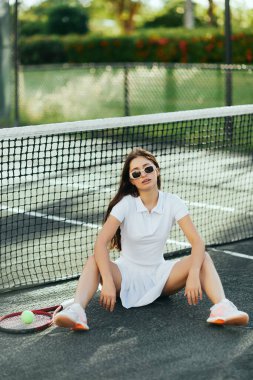 female player resting on tennis court in Miami, athletic young woman with brunette long hair sitting in white outfit and sunglasses near racket and ball, tennis net, blurred background, iconic city  clipart