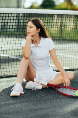 female tennis player resting after game in Miami, young woman with long hair sitting in white outfit near racket with ball and tennis net, blurred background, Florida, iconic city, tennis court  clipart