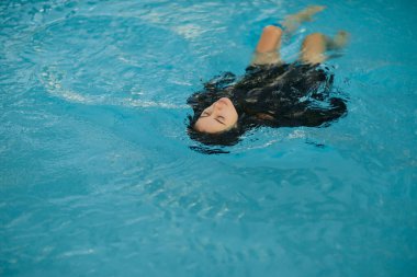Yaz tatili, siyah mayo giymiş kaygısız bir kadın Miami 'deki lüks bir tatil köyünde halka açık havuzda mavi suda yüzüyor, parlayan su, özgürlük, rahatlama, Miami' de tatil yeri. 