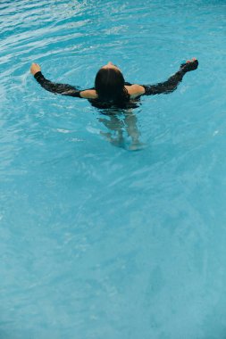 Yaz tatili, kaygısız esmer kadın Miami 'deki lüks bir tatil köyünde umumi havuzda yüzüyor. Parlak su, özgürlük, rahatlama, Miami' de tatil köyü. 