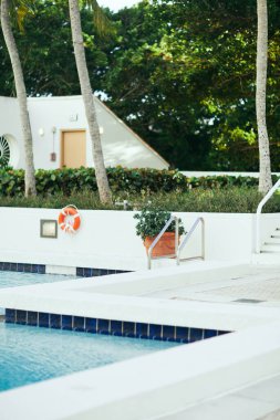 Lüks otel, halka açık yüzme havuzu parlak mavi su ve paslanmaz korkuluklu metal havuz merdiveni, bulanık arka plan, tatil ve tatil konsepti, açık hava eğlencesi. 