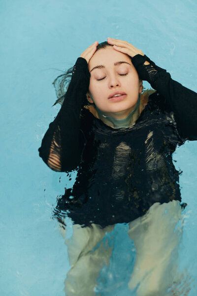 отсутствие макияжа, потрясающая и сексуальная брюнетка в черном вязаном наряде, позирующая внутри открытого бассейна во время отпуска в Майами, природная красота, роскошный курорт, Флорида, вид сверху