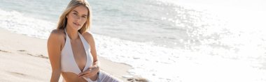 Sarışın genç bir kadın güneşli Miami Sahili 'nde beyaz bir bikiniyle dinginlik ve doğal güzelliğin vücut bulmuş hali..