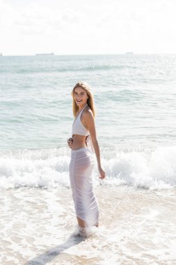 Güneşli bir günde Miami sahilinde zarif bir şekilde duran genç, güzel sarışın bir kadın..