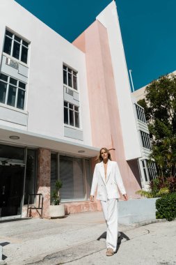 Genç, güzel sarışın bir kadın Miami 'de çarpıcı bir binanın önünde kendinden emin bir şekilde duruyor..