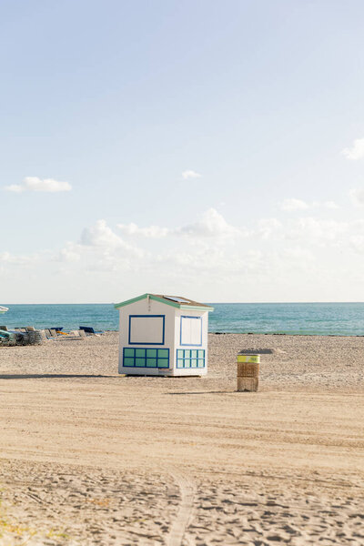 Хижина спасателя стоит высоко на песчаном пляже рядом с океаном, предлагая защиту и помощь пляжникам.