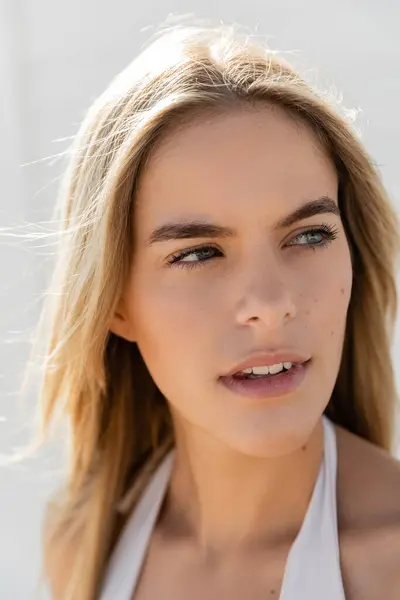 stock image A young and beautiful blonde woman with long hair wearing a white top dances on Miami Beach under the sun.