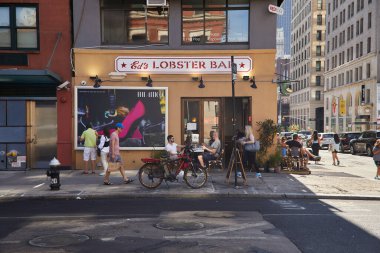 NEW YORK, USA - NOVEMBER 26, 2022: eds lobster bar, bicycle and pedestrians on walkway in soho clipart