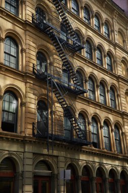 vintage building with fire escape stairs and arch windows in new york city, autumnal scene clipart