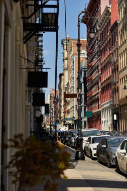 New York 'un şehir merkezindeki klasik binalarla dolu rahat cadde boyunca park edilmiş arabalar.