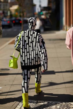 NEW YORK, USA - NOVEMBER 26, 2022: Back view of trendy extravagant person walking along street in new york city, urban style clipart